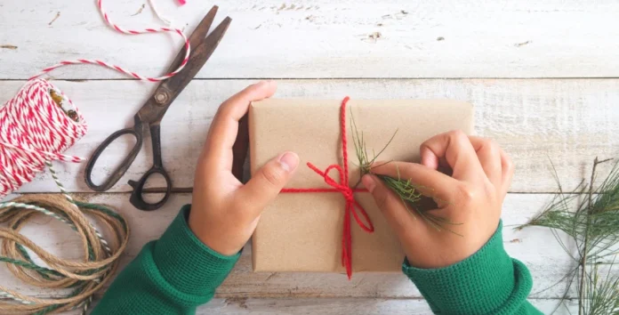 Duas mão a fazer um laço numa prenda de Natal